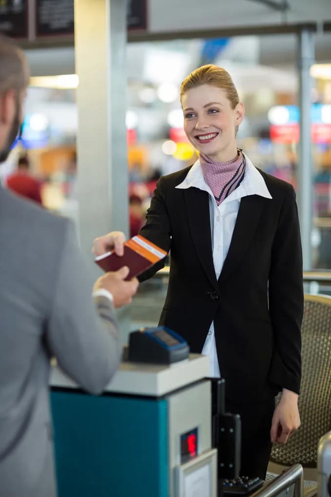 An airline attendant handing a passport back at check-in