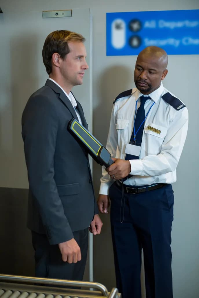 A security officer screening a departing traveler at an airport checkpoint