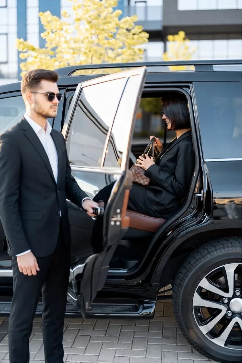 A chauffeur opening the car door for a business traveler