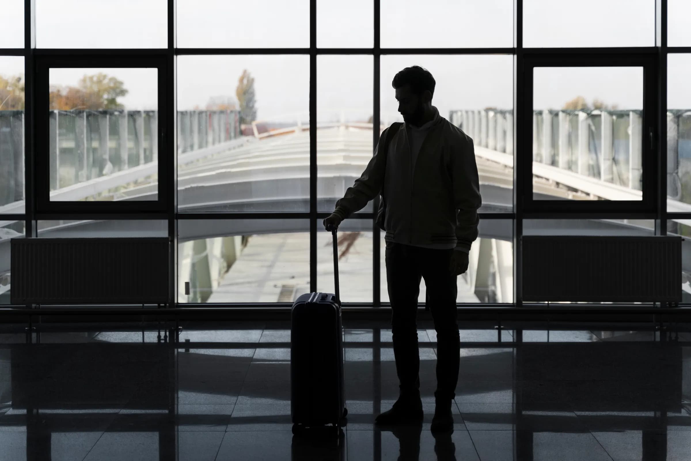 A traveler with luggage walking through an airport arrivals walkway