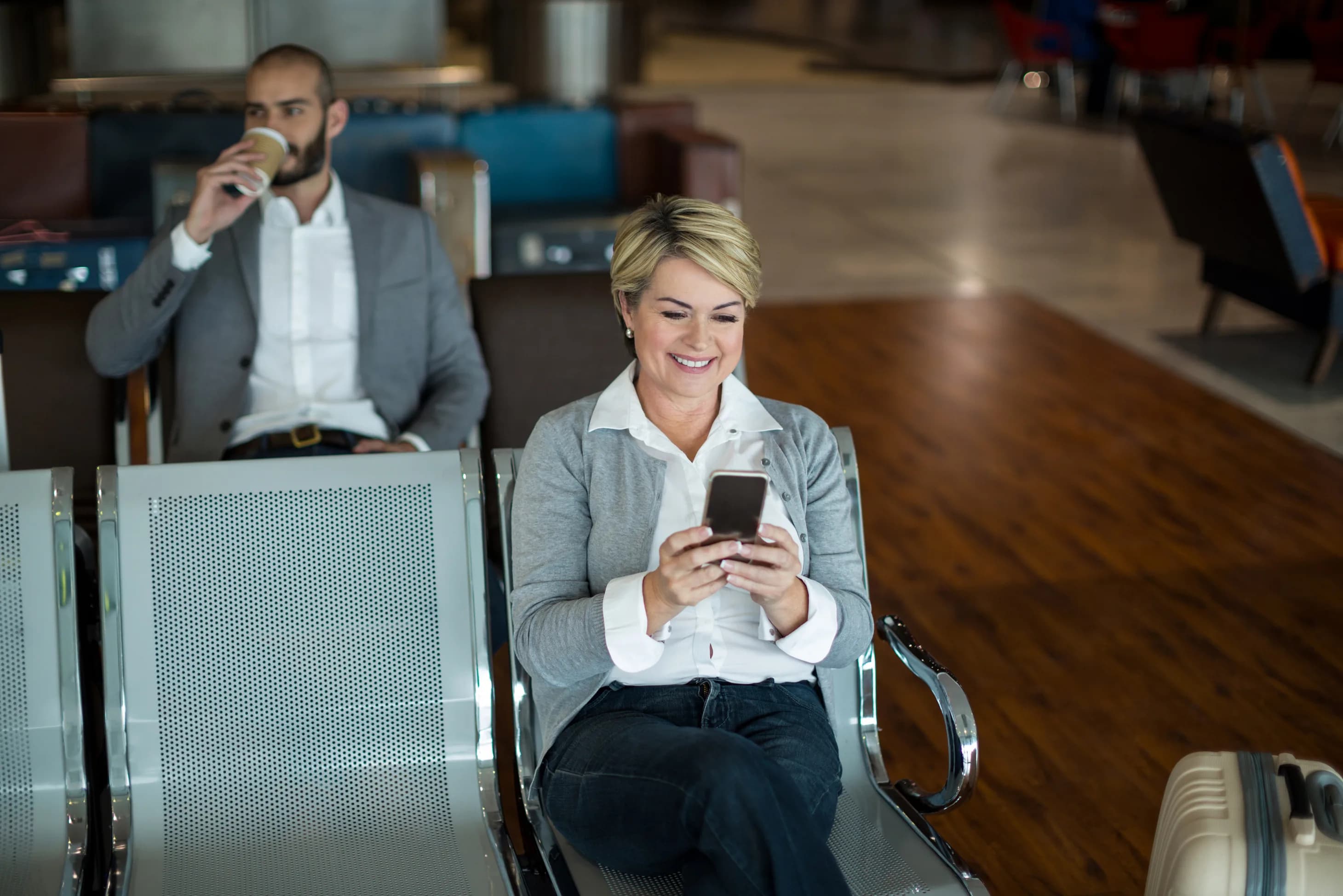 A business traveler using her phone in an airport waiting area