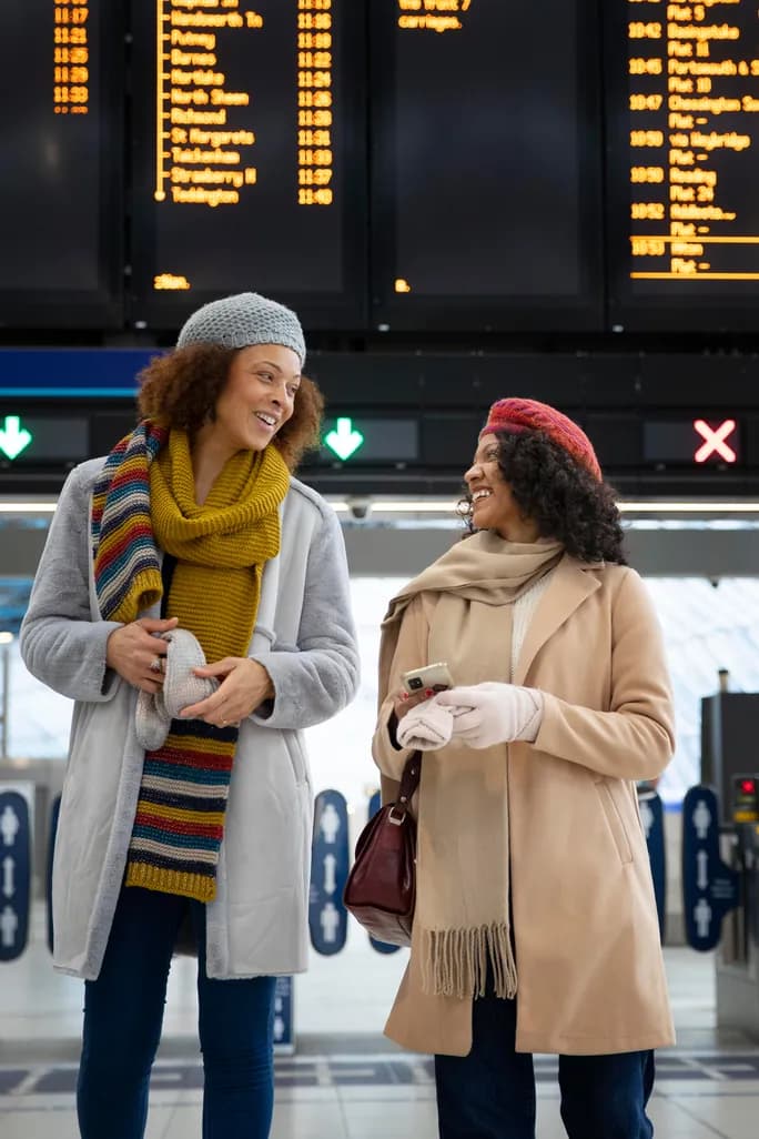 Two travelers talking in front of the departure boards
